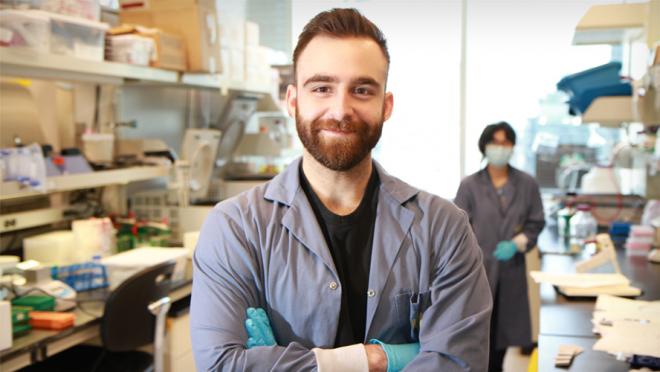 Image of man with beard in a laboratory crossing his arms and smiling