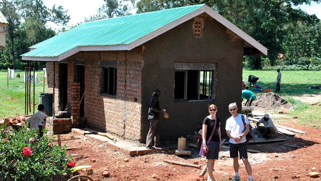 Photograph of Drs. Kevin Kain (right) and Andrea Conroy (left) in front of a pediatric ICU in Uganda as it is being built. 