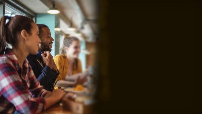 People smiling at a cafe with the right side of the image blacked out to demonstrate how people with hemianopsia would view the scene.