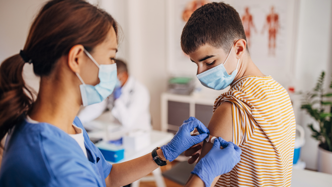 A boy in a doctor's office getting a vaccine from a healthcare provider