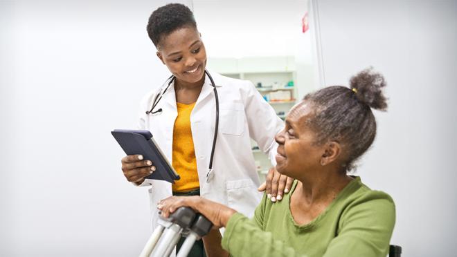 Healthcare professional smiling with a patient who is holding crutches and smiling
