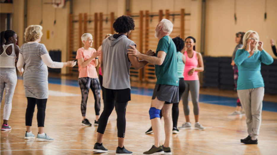 Group of older adults laughing and smiling together in a group exercise class.
