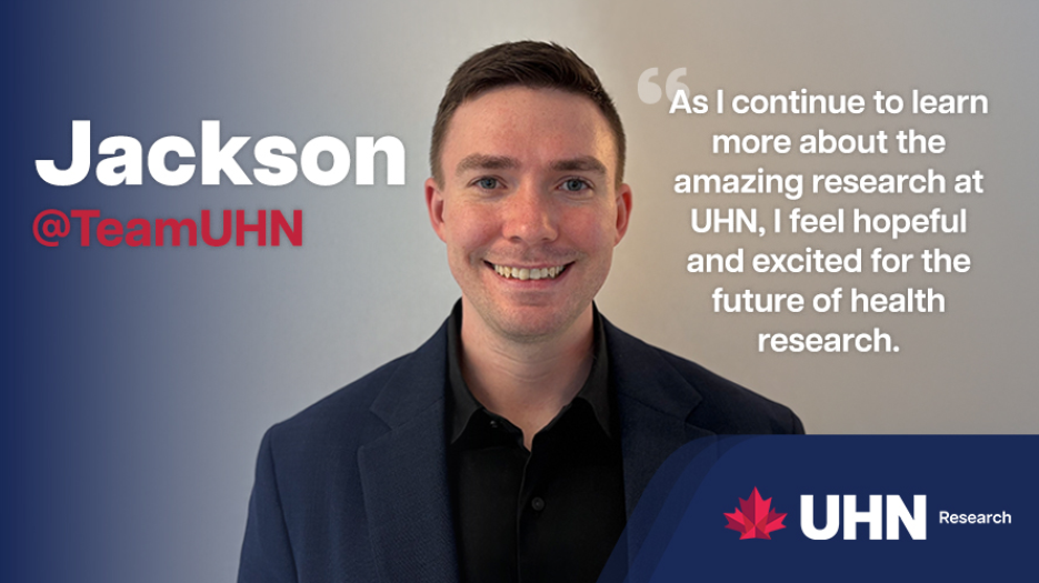 Smiling man in dark suit jacket in front of blank white wall