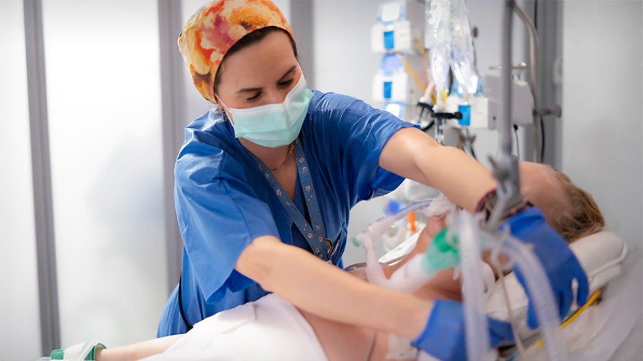 Health care worker adjusts ventilator of patient in the hospital.