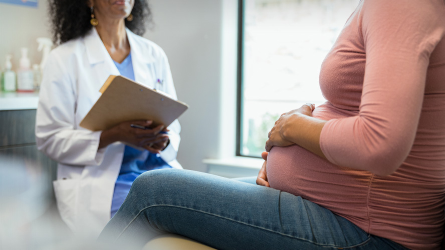 Clinician sitting in clinical room with pregnant woman.