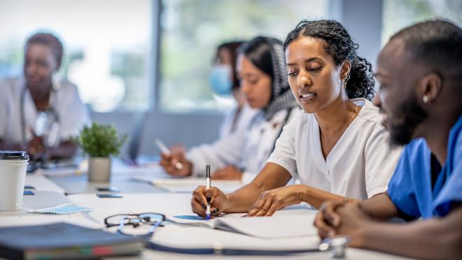 health care providers have a group discussion while looking at information on papers on the table