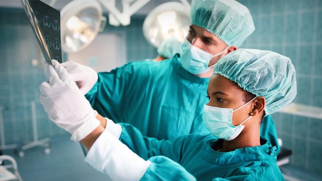 Image of two surgeons looking at medical images during surgery in the operating room.